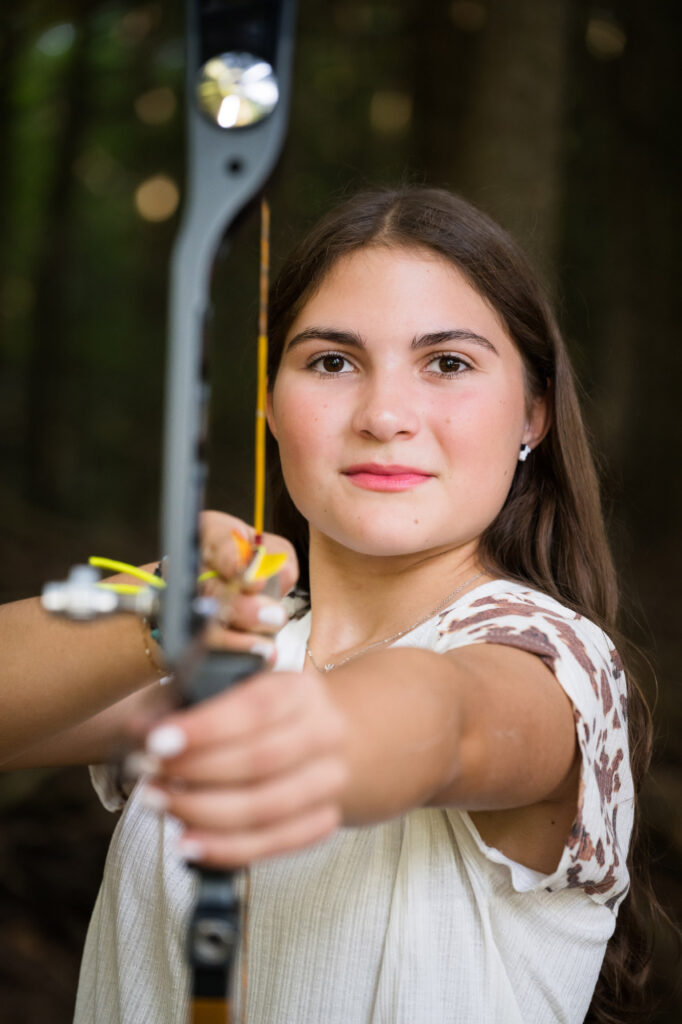 Canton High School senior Bella posing with her bow and arrows during outdoor senior photo session by a Northern NY photographer.