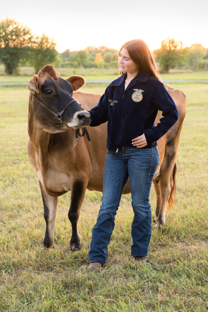 Canton Dairy Princess Bella posing proudly with her cow at the dairy farm during her senior photo session.